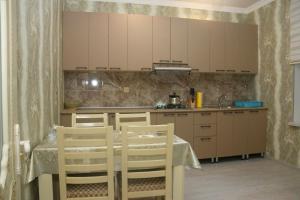 a kitchen with a table and white cabinets and a table and chairs at Golden House in Gabala