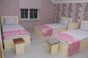 a room with three beds and a window at Golden House in Gabala