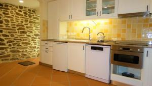 a kitchen with white appliances and a stone wall at Casa CÔA - Casas de Villar - Rural Experience in Vilar de Amargo