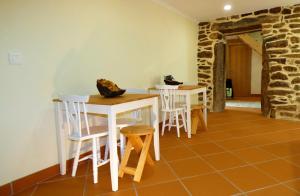 una stanza con tavoli e sedie bianchi e un muro in pietra di Casa CÔA - Casas de Villar - Rural Experience a Vilar de Amargo