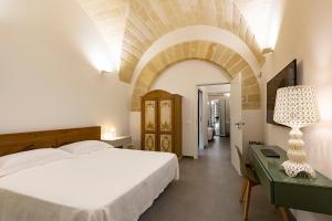 ein Schlafzimmer mit einem Bett und einem Tisch mit einer Lampe in der Unterkunft Palazzo Guajana in Trapani