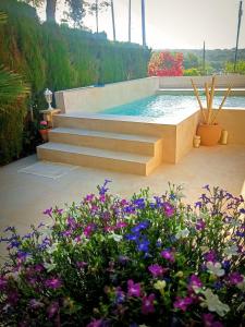 a swimming pool with stairs and flowers in a garden at Ca la Carmeta in Cunit