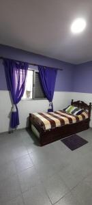 a bedroom with a bed with purple walls and a window at Tomay Apart in Santa Fe