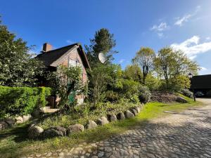 a brick house with a garden next to a street at Ferienhaus unter Reet im Heidedorf Sankt Dionys bei Lüneburg in Sankt Dionys
