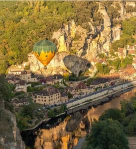 a hot air balloon is flying over a river at Le Studio des Gîtes Aérostier in La Roque-Gageac