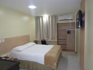 a bedroom with a bed and a desk with a television at Arrey Fórmula Hotel - Itaueira in Piriperi