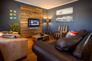 sala de estar con sofá de cuero y TV en Modern Shabby Chic Apartment, en Durbanville