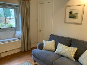 a living room with a blue couch and a window at Masons Cottage, an Idyllic retreat in an area of outstanding beauty, close to Blenheim Palace, Oxford & The Cotswolds in Stonesfield