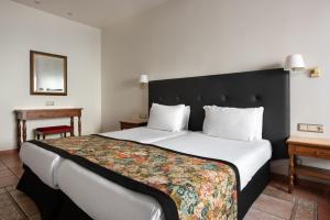 a bedroom with a large bed with a black headboard at Exe Alfonso VIII in Plasencia
