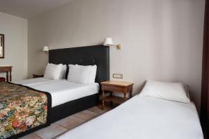 a hotel room with two beds and a table at Exe Alfonso VIII in Plasencia