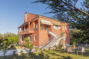 an orange house with stairs and tables and chairs at Villa Vasiliki in Lefkímmi
