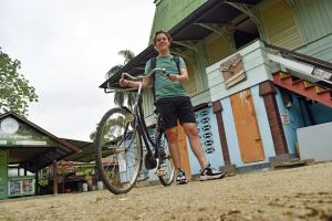 une femme tient un vélo devant un bâtiment dans l'établissement Zus&Zo, à Paramaribo