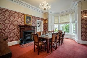 uma sala de jantar com uma mesa e cadeiras e uma lareira em Annfield House, Callander em Callander