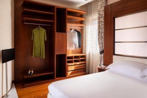 a bedroom with a bed and a green dress on a rack at Repubblica Firenze Luxury Apartments | UNA Esperienze in Florence