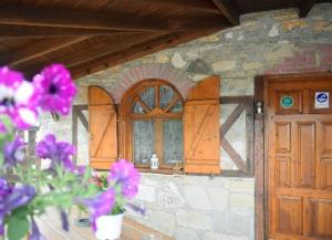 a stone house with wooden doors and purple flowers at Mountain House Kastro in Kástron