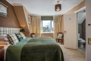 a bedroom with a bed with a green blanket and a window at Annfield House, Callander in Callander