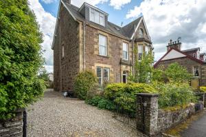 uma velha casa de tijolos com uma cerca em frente em Annfield House, Callander em Callander