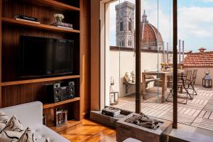 - un salon avec une télévision et une grande fenêtre dans l'établissement Repubblica Firenze Luxury Apartments | UNA Esperienze, à Florence