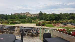 eine Terrasse mit Tischen und Stühlen und Blick auf ein Schloss in der Unterkunft Carcassonne Guesthouse in Carcassonne