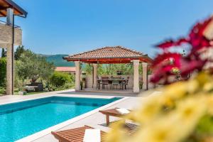 a swimming pool with a gazebo and a table and a swimming pool at APARTMENT AMELIA VRPOLJE in Vrpolje