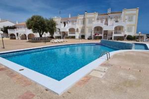 uma piscina em frente a um grande edifício em Apartamento Castellsol 106 em Arenal d'en Castell