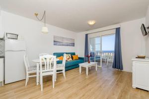 Una sala de estar con un sofá azul y una mesa. en Apartamento Castellsol 106, en Arenal d'en Castell