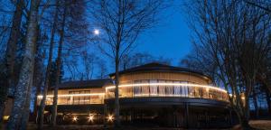 a large building with lights in the woods at night at Ramside Hall Hotel, Golf & Spa in Durham