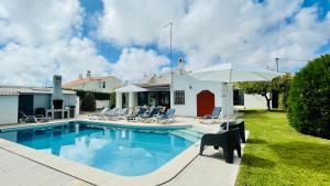 a house with a swimming pool with chairs and an umbrella at Strip - Private Pool - 12 Guests - Albufeira in Albufeira