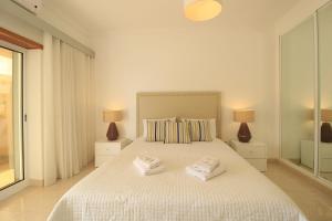 ein weißes Schlafzimmer mit 2 Handtüchern auf dem Bett in der Unterkunft Armação de Pêra Brightness With Pool by Homing in Armação de Pêra