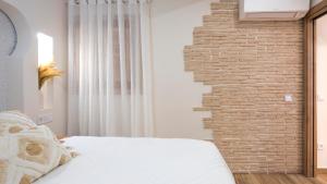 een slaapkamer met een bakstenen muur en een bed bij Apartamento ruh sara by Toledo AP in Toledo