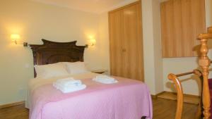 una camera da letto con un letto rosa e asciugamani di Casa CÔA - Casas de Villar - Rural Experience a Vilar de Amargo