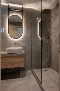 uma casa de banho com um chuveiro, um lavatório e um espelho. em Asteras Hotel em Sarti