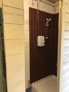 a shower in a bathroom with a brown wall at The Kestrel Shepherd Hut, Whitehouse Farm in Stowmarket