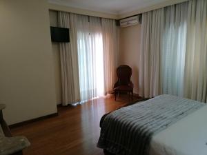 a bedroom with a bed and a chair and a window at Colina do Ave Alojamento Local in Ribeirão