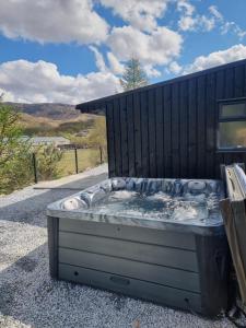 a hot tub sitting outside of a black building at Cosy Annex with Hot tub and Separate Bedrooms in Kinlochleven