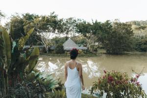 Una mujer con un vestido blanco caminando por un estanque en Makenke Hostel By Los Colores Ecoparque en Doradal