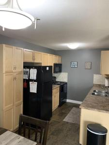 a kitchen with a black refrigerator and wooden cabinets at Chris Cozy Condo Lebay Regina in Regina