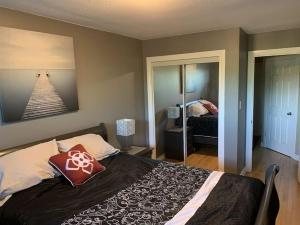 a bedroom with a bed with a red pillow on it at Chris Cozy Condo Lebay Regina in Regina