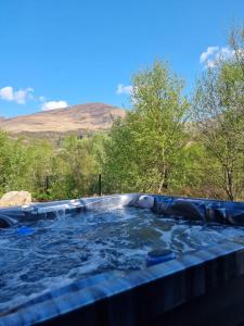 a hot tub with a mountain in the background at Cosy Annex with Hot tub and Separate Bedrooms in Kinlochleven