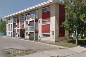 an apartment building with red doors on a street at Chris Cozy Condo Lebay Regina in Regina