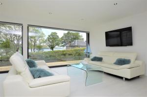 a living room with two white chairs and a tv at The Lookout in Tighnabruaich