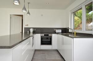 a white kitchen with white cabinets and a sink at The Lookout in Tighnabruaich