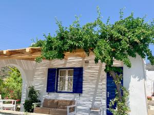 una casa bianca con finestre blu e un albero di Spiti Apartment a Mylopotas