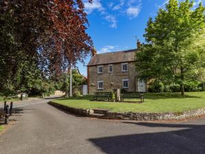 an old house with two benches in front of a road at Old Rectory Cottage in Lincoln
