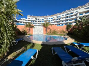a hotel with a pool and chairs and a building at Puerto de la Duquesa MINIMUM 3 NUITS in Manilva
