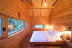 Ce lit se trouve dans une chambre en bois dotée d'une fenêtre. dans l'établissement Granaries Pear & Walnut, à Tolmin