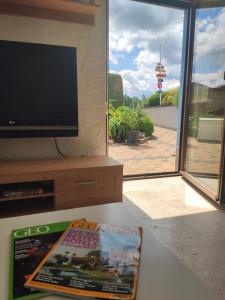 a living room with a television and a magazine on a table at Emyda' s Tropical Home at Goldsteig trail in Wiesau