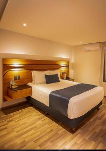 - une chambre avec un grand lit et une tête de lit en bois dans l'établissement Hotel Boutique Maria, à Morelia