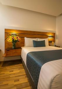 - une chambre avec un grand lit et un vase de fleurs dans l'établissement Hotel Boutique Maria, à Morelia