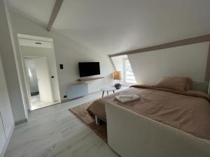 um quarto branco com uma cama e uma televisão em Maison/ Loft familial à Etretat em Étretat